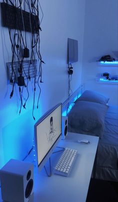 a desk with a computer and speakers on it in a room that is lit up