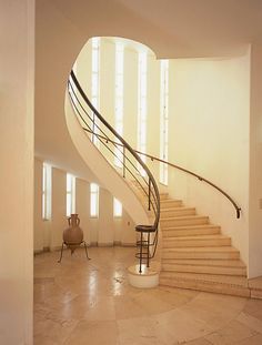 a spiral staircase in an empty room with white walls and floor tiles on the ground