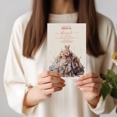 a woman holding up a card with an image of a dress on it and flowers in front of her