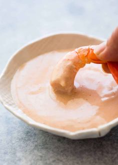 a person dipping some kind of sauce in a bowl