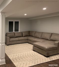 a living room with a large sectional couch in the corner and a rug on the floor