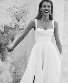 a woman in a white dress is posing for the camera with her arms spread out