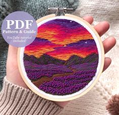 a person holding up a small embroidery project with mountains in the background and text overlay that reads, pattern & guide you'll use material included