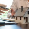 two hands are holding keys to a model house