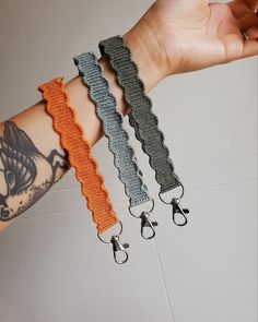 three different bracelets on someone's arm, one with an orange and gray ribbon