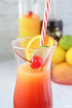 a glass filled with orange juice and topped with a cherry