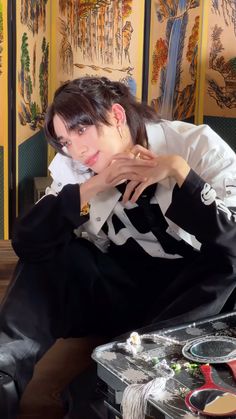 a woman sitting on top of a table next to a suitcase