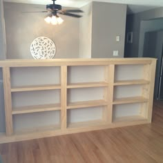 an empty room with a ceiling fan and bookcases on the floor in front of it