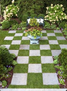 a checkerboard pattern in the middle of a garden with flowers and greenery