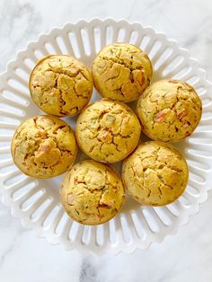 several muffins on a white platter sitting on a marble counter top, ready to be eaten