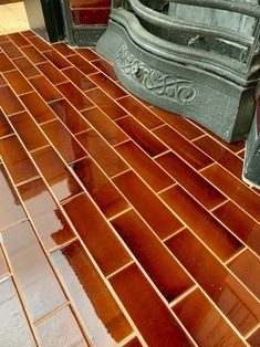 a close up view of a shiny brown tile floor with an old statue in the background