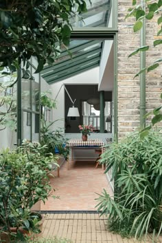 an outdoor area with plants and a table in the center, surrounded by greenery