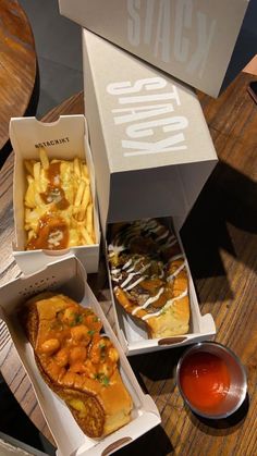 three boxes with different types of food in them on a wooden table next to some dipping sauce