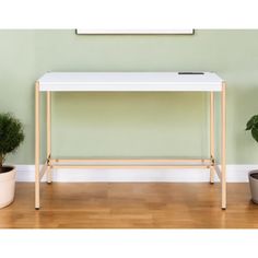 a white table sitting on top of a hard wood floor next to a potted plant