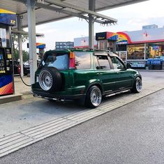 a green car parked at a gas station