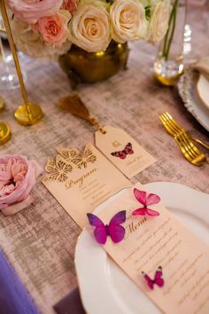 the table is set with pink flowers and gold place settings for guests to sit at