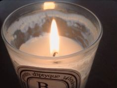 a lit candle sitting on top of a table next to a black background with the letter b in it