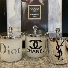 three silver canisters sitting on top of a table next to a chanel sign