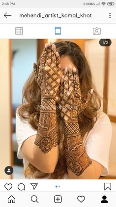 a woman holding her hands up to her face with mehndi designs on it