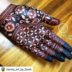 a close up of a person's hand on a wooden table with an intricate design