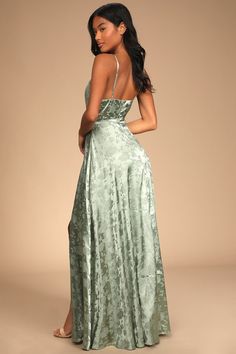 a woman in a green dress is standing up and looking at the back of her dress