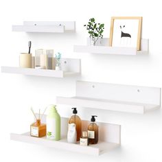 three white shelves with soaps, lotion and other bathroom items on them against a white wall