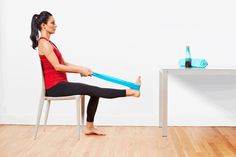 a woman sitting on a chair with a blue yoga tube in her hand and another person standing next to the table