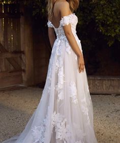 a woman in a white wedding dress standing outside