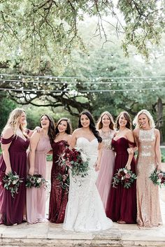 a group of women standing next to each other wearing dresses and holding bouquets in their hands