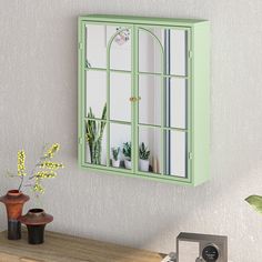 a green window frame with potted plants in front of it and a mirror on the wall