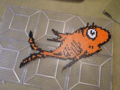 an orange and black fish made out of perforated wire on a table top