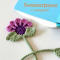 a crocheted flower is next to a book with the word sommerpause written on it