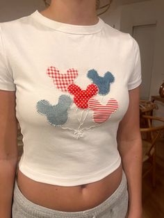 a woman wearing a mickey mouse t - shirt with red, white and blue hearts on it