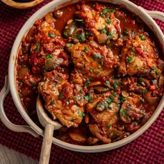 a large pot filled with meat covered in sauce and garnished with parsley