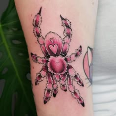 a woman's arm with a pink spider tattoo on it and hearts in the center