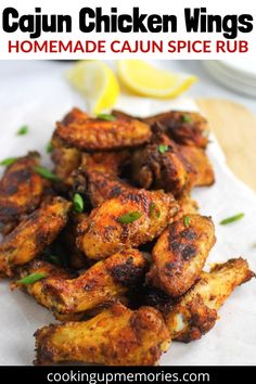 some chicken wings are on a piece of paper with lemon wedges next to it