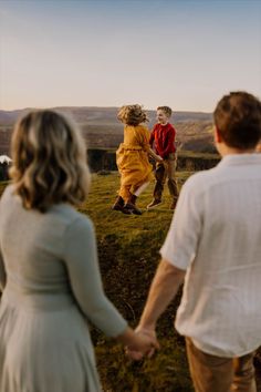 two people holding hands while walking across a field