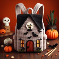 a crocheted house with bats and pumpkins around it