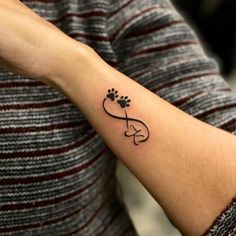 a woman's arm with a tattoo on it that has a dog paw and heart