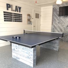 a ping pong table in the middle of a room with a tv on the wall