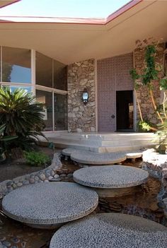 a house that has some rocks in front of it and plants on the ground next to it