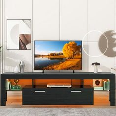 a flat screen tv sitting on top of a wooden table next to a wall with pictures