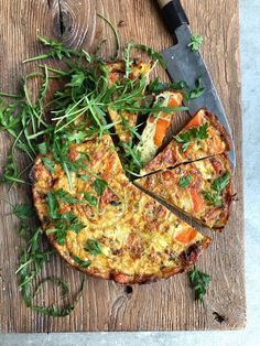 a pizza sitting on top of a wooden cutting board next to a knife and fork