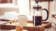 two cups of coffee on a tray with pastries