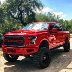 a red truck is parked in the dirt