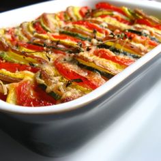 a casserole dish with red and yellow peppers in it sitting on a table