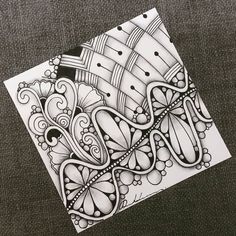 an intricately designed piece of paper on top of a gray surface with black and white ink