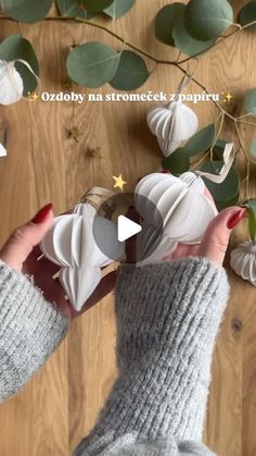 someone holding up some paper flowers on top of a wooden floor