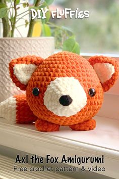 an orange crocheted stuffed animal sitting on top of a window sill next to a potted plant