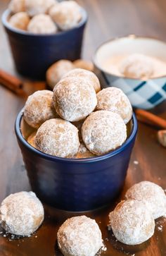 powdered sugar covered donuts in blue bowls with cinnamon sticks on the table next to them